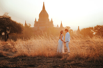 Couple standing and looking at Bagan temple in Myanmar archaeological zone at sunset.