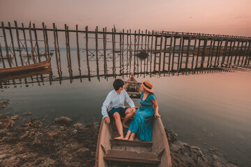 Couple taking a sightseeing boat trip at U Bein Bridge, Myanmar in the morning.