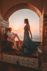 Couple sitting and admiring the view from above at Mandalay Hill, Myanmar during sunset.