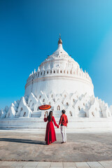 A couple visits the white Hsinbyume Pagoda during sunset in Myanmar.