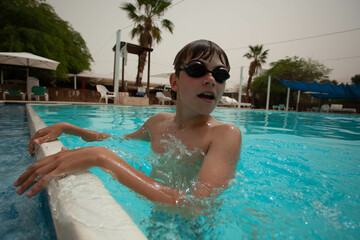 Boy with glasses swims in the pool