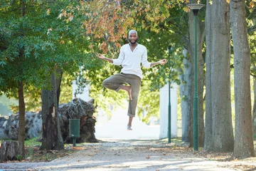 Foto op Plexiglas Man, levitate and meditation with yoga outdoor, portrait or exercise in park with health and healing. Spiritual, flying in air and African yogi with workout, wellness and mindfulness in nature © peopleimages.com