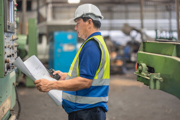 Senior Engineer Analyzes Blueprint for Machine Maintenance in Industrial Factory Setting