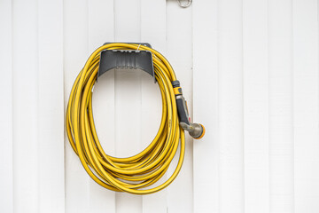 Yellow garden hose hanging on a house wall.