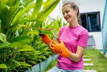 A young woman takes care of the garden, waters, fertilizes and prunes plants - 790592473