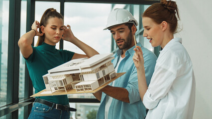 Skilled engineer holds house model and explain about house construction to skilled manager. Group...