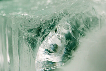Chrystal clear frosty textured natural ice block in cold light green tones, isolated on black background.