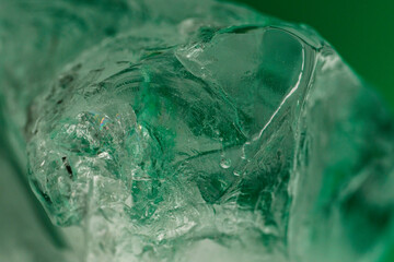 Chrystal clear frosty textured natural ice block in cold light green tones, isolated on black background.