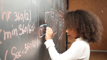 Site view of young african girl writing engineering prompt or code on blackboard. Skilled smart...