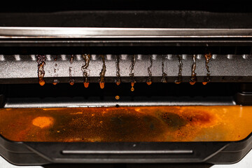 closeup of fat draining from the electric grill