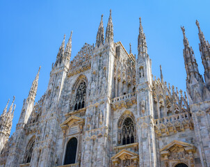 Cathedral Duomo di Milano with spires on Piazza del Duomo square in historical city centre with blue sky background in clear sunny day. Main facade of Milan Cathedral close-up with details