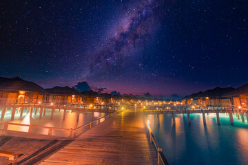Luxury over water villas, bungalows sea ocean with beach at night sunset time, Milky Way. Exotic adventure carefree travel vacation, summer resort landscape. Fantasy nature resort hotel landscape
