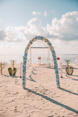 Bride and groom, newlyweds, honeymoon on dreamy beach sunset sun under wedding arch flowers. Love married young couple by the sea. Destination wedding ceremony on tropical island romantic sunlight - 790613294