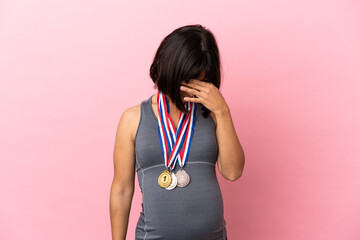 Pregnant mixed race woman with medals isolated on pink background with tired and sick expression