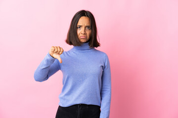 Young latin woman isolated on pink background showing thumb down with negative expression