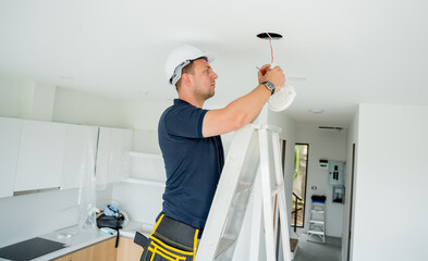 technician is installing an LED spotlight in the ceiling. - 790623820