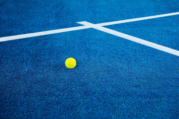 Closeup of one yellow tennis ball or paddle tennis and white lines on blue court. Horizontal sport poster, greeting cards, headers, website