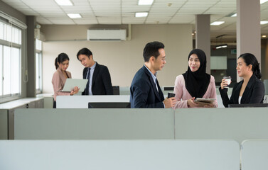 Asian man and two women office employee working on digital tablet PC while standing in open space office with blurred colleagues working on laptop in background - 790624659