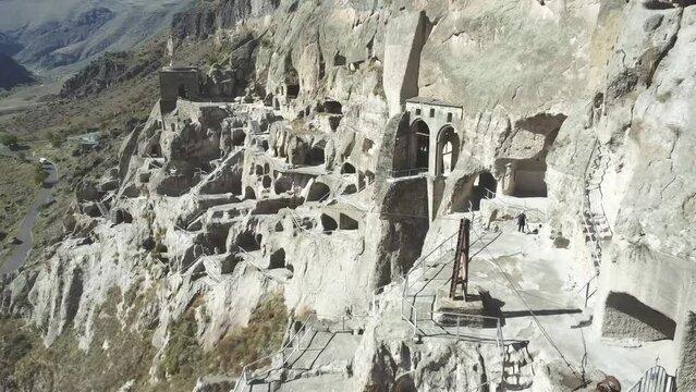 Drone video captures the ancient cave city in Georgia, with intricate dwellings carved into a rocky cliff face, a testament to historic human ingenuity and culture.