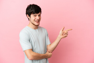 Young Russian man isolated on pink background pointing finger to the side