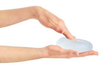 Hand pressing soft breast implant in hand on white background