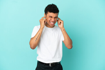 Young African American man isolated on blue background frustrated and covering ears
