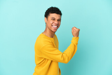 Young African American man isolated on blue background celebrating a victory