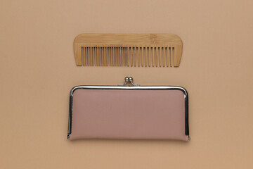 Wooden comb and a woman's purse on a beige background.