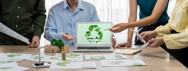Recycle sign displayed on green business laptop while business team presenting green design to...