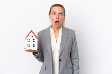 Real estate agent woman holding a toy house isolated on white background looking up and with...