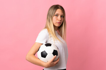 Young blonde woman isolated on pink background with soccer ball