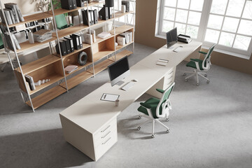 Top view of coworking interior with pc monitors and armchairs in row, window