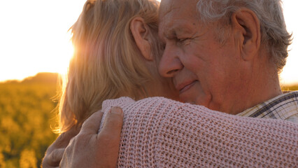 Elderly gray haired caucasian man lovingly hugs wife tightly. Happy couple celebrating anniversary....