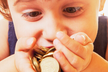 Happy beautiful little business child girl sniffs coins. Purposefulness, motivation, wealth, success, freedom concept.