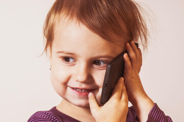 Little smiling beautiful child girl is speaking with smart phone - 790641601