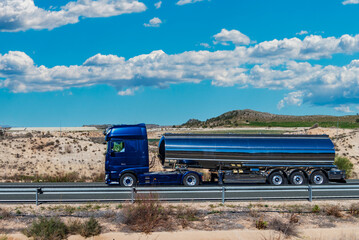 Tanker truck for transporting food liquids traveling on a highway, side view.