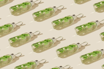Pattern from water drink detox with green mint leaves in glass bottle at sunlight on beige...