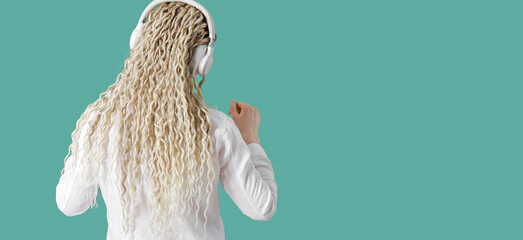 Modern stylish girl woman in headphones on head, listening to music and dancing, blonde long curly...