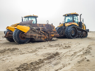 Bulldozer giallo sulla sabbia in primavera prepara la spiaggia per l'estate - obrazy, fototapety, plakaty