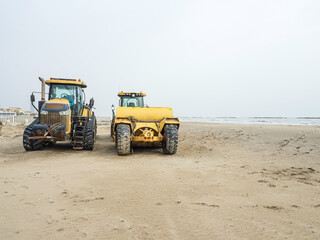Fototapeta na wymiar Bulldozer giallo sulla sabbia in primavera prepara la spiaggia per l'estate