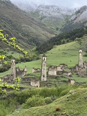 View of the medieval Targim tower complex in the Caucasus mountains surrounded by greenery. The Caucasus Mountains on a cloudy day in Ingushetia. Russia