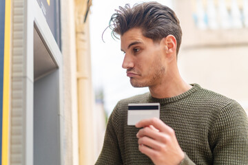 Young caucasian man at outdoors using an ATM