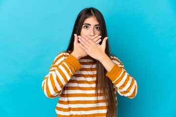 Young caucasian woman isolated on blue background covering mouth with hands