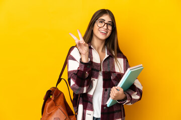 Young student woman isolated on yellow background smiling and showing victory sign