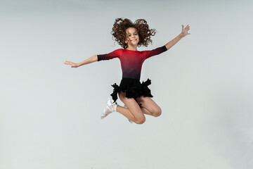 curly-haired girl engaged in ballroom dancing jumps up with joyful and mischievous emotions