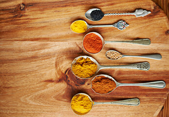 Spoons, spice and selection of ingredients for seasoning on kitchen table, turmeric and paprika for...