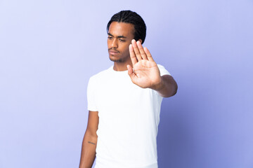 Fototapeta premium Young African American man with braids man isolated on purple background making stop gesture and disappointed
