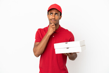African American pizza delivery man picking up pizza boxes over isolated white wall having doubts...