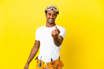 African American electrician man over isolated yellow wall doing coming gesture