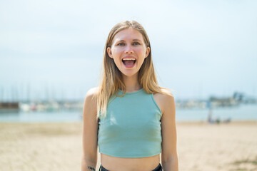 Young blonde woman at outdoors with surprise facial expression
